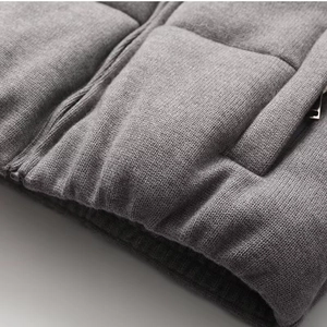 Close-up of gray knitted quilted jacket showing fabric texture and silver zipper detail