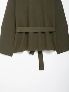 Detailed macro view of olive green knitted texture and matching belt design on a short cardigan
