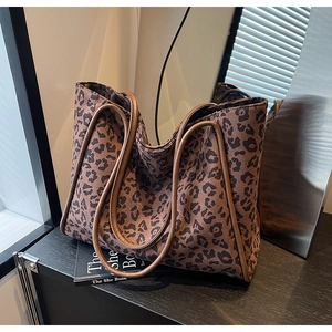 Chic leopard print tote bag with brown leather trim shown in a stylish indoor setting