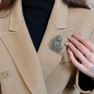 Close-up of retro hollow horse head brooch with rhinestones on a camel wool coat