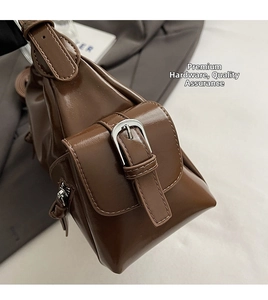 Detail of vintage dark brown leather shoulder bag with textured silver metal buckle