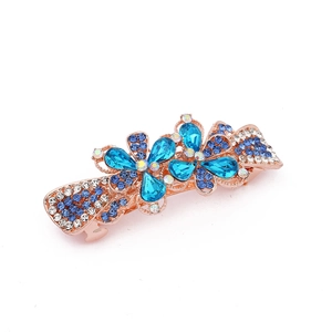Detail of rose gold hair clip with blue and white crystal flowers on white background