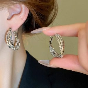Three-layered silver twisted hoop earrings with textured finish worn by a model