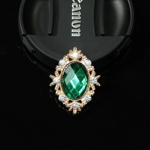 Macro detail of oval green gemstone brooch with gold frame and sparkling rhinestones