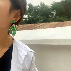 Close-up of Santa Claus pattern acrylic earring worn by a model for Christmas style