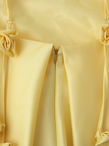 Detail view of the yellow satin dress back showing a hidden zipper and 3D floral accents
