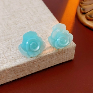 Vue macro des boucles d'oreilles roses en résine bleu clair sur tissu beige