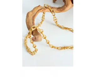 Detailed view of gold plated titanium geometric link chain draped over wooden branch