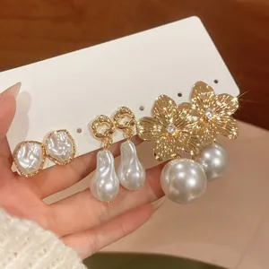 Close-up of gold flower and baroque pearl earring set on a white display card