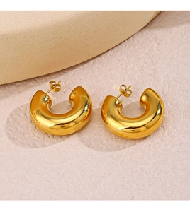 Detailed view of chunky 18K gold plated C-shape hoop earrings on a stone pedestal