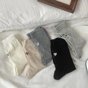 Detail view of five assorted knit socks with heart embroidery and ruffled edges