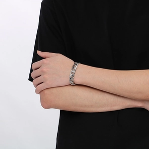 Gros plan d'un bracelet gourmette en acier inoxydable argenté porté avec un t-shirt noir