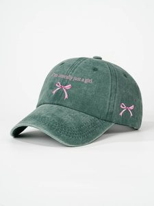 Detail of pink bow embroidery and 'I'm literally just a girl' text on washed green cap