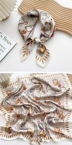 Detail view of a silk square scarf featuring cute cartoon cat patterns and soft grey tones