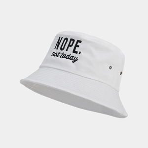 Close-up of white cotton bucket hat featuring black 'NOPE' embroidery and metal eyelets