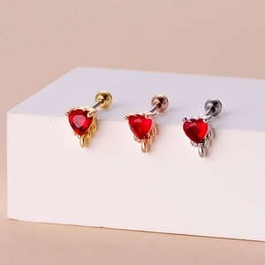 Detail of three heart-shaped red zircon screw back earrings in gold, rose gold and silver