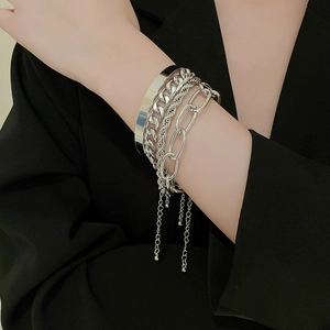 Detail view of silver multi-layered metal chain bracelet set worn over black blazer sleeve