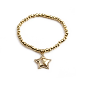Bracelet à perles dorées avec breloques étoile et lune serties de zircon sur fond blanc