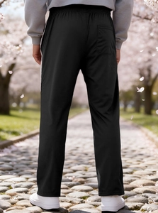 Detail of men's black sports pants with elastic waist and back pocket on cherry blossom path