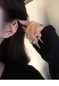 Macro shot of silver ear cuff with M-shaped logo and sparkling zircon stones on model ear