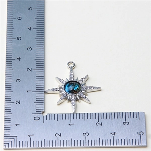 Octagonal star pendant with blue gemstone and crystals measured on a metal ruler