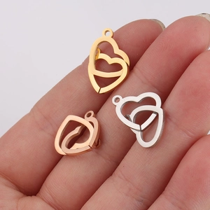 Three double heart charms in gold, rose gold and silver finish on hand for scale