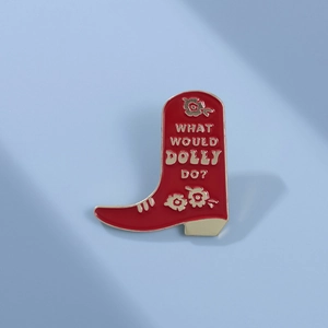Red enamel cowboy boot brooch with What Would Dolly Do text on a light blue background