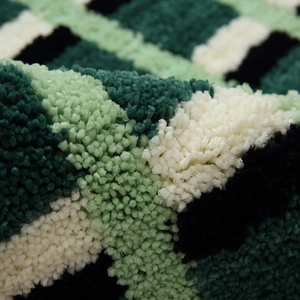 Absorbent checkered bath mat with soft plush texture in green and white tones