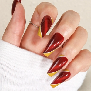 Macro detail of burgundy cat-eye coffin nails with gold and white diagonal stripes