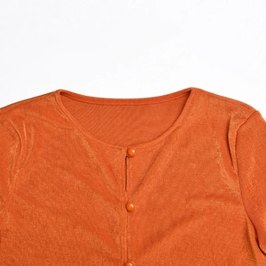 Détail du haut court en velours orange avec col rond et boutons assortis