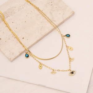 Close-up of double layer gold necklace with blue teardrop and eye shaped charms