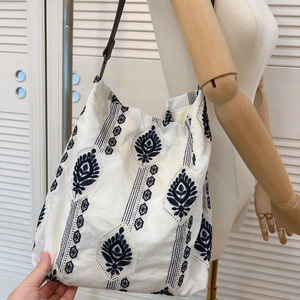 Detail of bohemian embroidery and dark brown leather strap on cotton linen tote bag