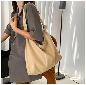 Close-up of large beige leather tote bag draped naturally over model's shoulder