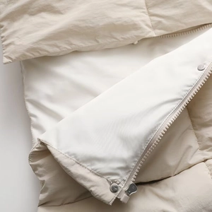 Detail of premium beige knit patchwork coat showing high-quality metal buttons and zipper
