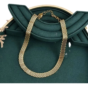 Elegant gold woven mesh chain necklace with lobster clasp on dark green background