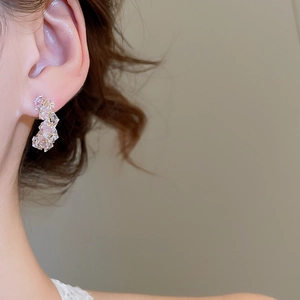 Detailed close-up of a model wearing C-shaped crystal beaded earrings with clear finish
