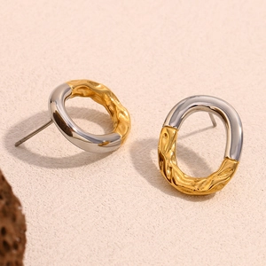 Dettaglio di orecchini ovali bicolore con finiture in oro ondulato e argento liscio