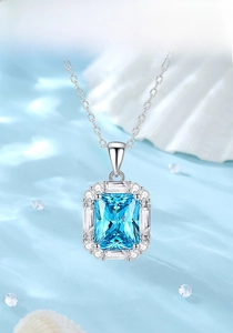 Detail of emerald cut light blue gemstone pendant on rippled silk fabric background
