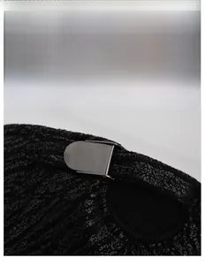 Dettaglio della fibbia in metallo del cappellino nero e della trama del tessuto caldo