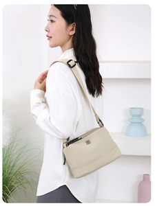 Sac à bandoulière en nylon beige avec logo floral porté par un mannequin en décor épuré