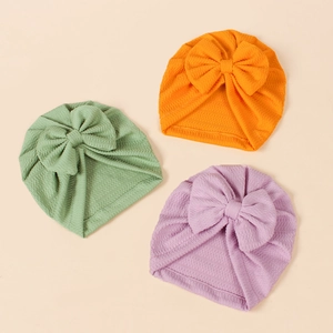 Detail of ribbed knit baby turbans with large bows in orange, green and purple colors