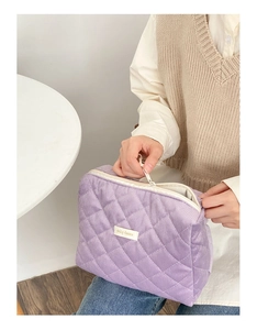 Vue macro de la trousse à maquillage matelassée violette avec étiquette de marque