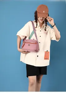 Close-up of pink nylon crossbody bag with durable zippers and wide jacquard strap