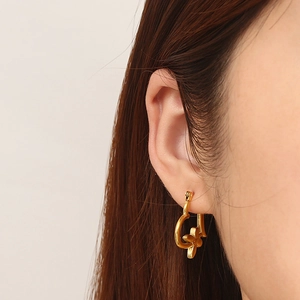 Detail shot of a gold heart-shaped earring with a central flower worn on ear