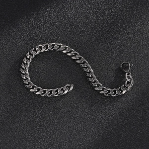 Detailed view of silver stainless steel Cuban link bracelet on black leather background