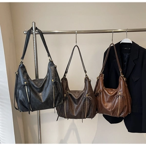 Detailed view of large leather hobo bags in black, coffee, and brown on a metal rack