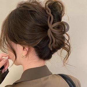 Elegante molletta per capelli a onde marrone opaco mostrata in uno chignon classico