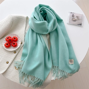 Detail shot of mint green cashmere-style scarf with soft tassels on tweed jacket
