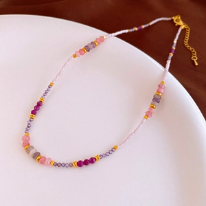 Detail of handmade beaded necklace featuring purple and pink stones with gold lobster clasp