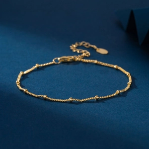 Detail of gold beaded bracelet featuring a minimalist rope chain and lobster clasp